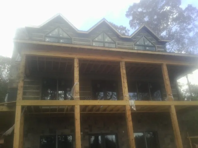 Dormers and porch framing on a large log home under construction — Roof Coating work by our crew in Edelstein