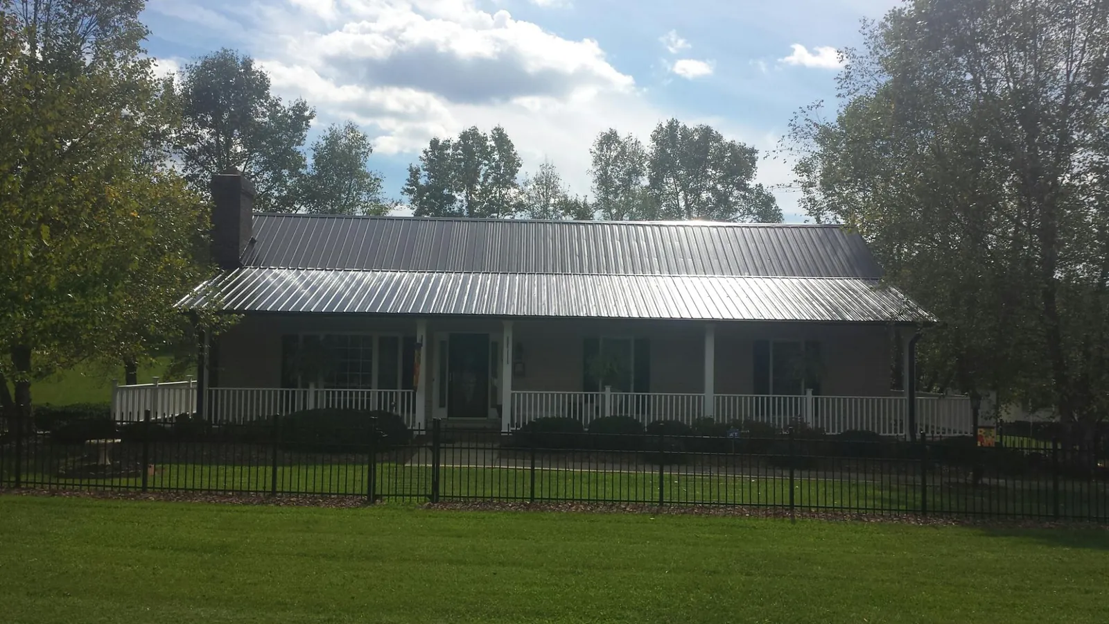 Gray metal roof on a brick ranch with a full width front porch — Gutter Guard Installation work by our crew in Edelstein