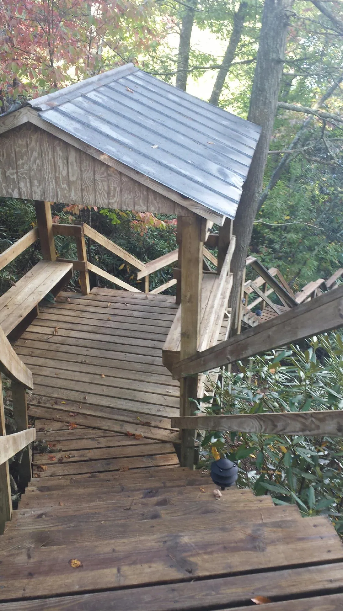 Metal roofed shelter over wooden steps on a wooded walkway — Skylight Repair & Installation work by our crew in Edelstein