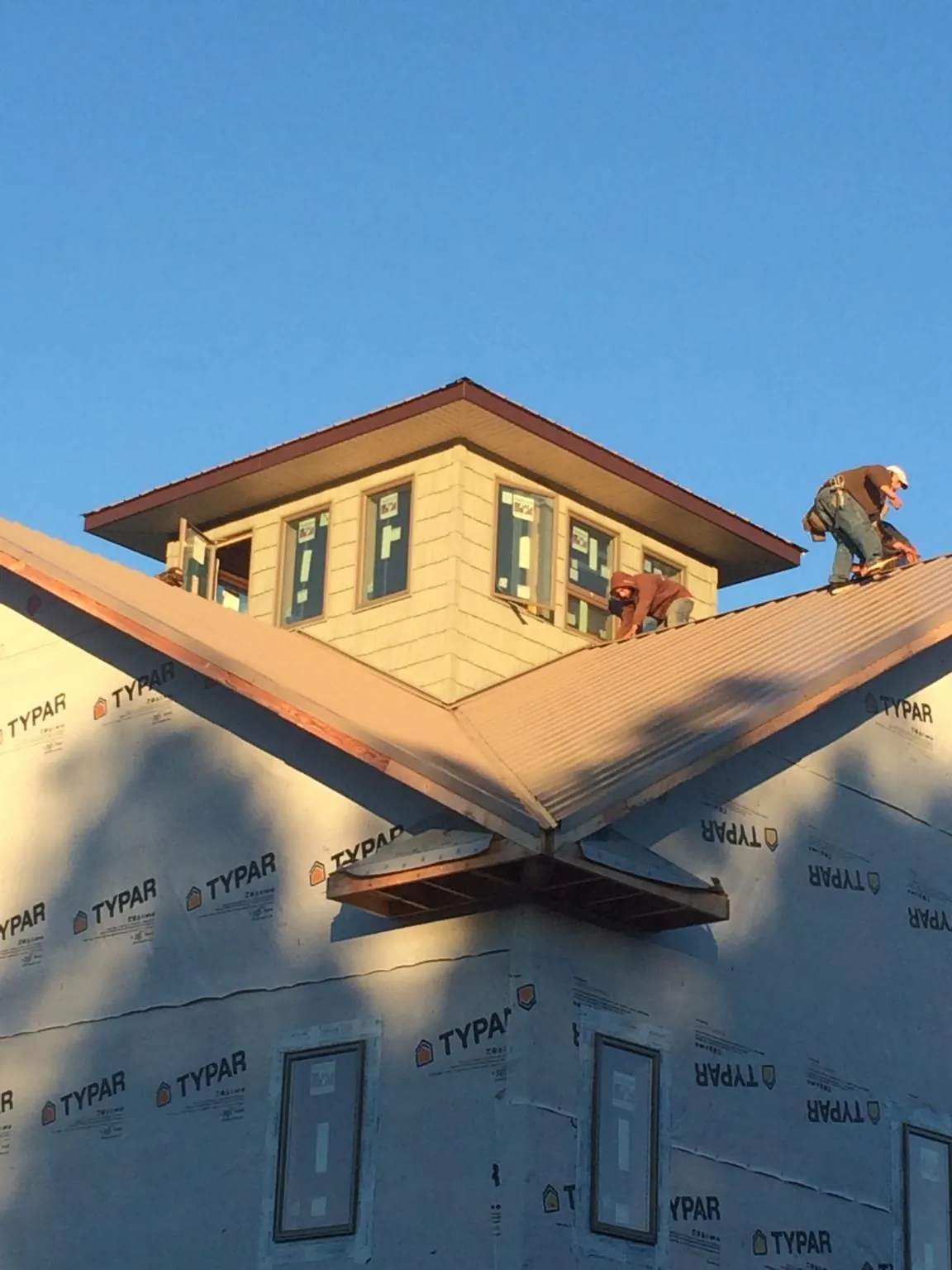 Roofers working around a rooftop cupola on a new metal roof at sunset — Roof Waterproofing in Edelstein by Roofing Brothers